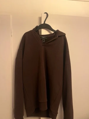 Brun hoodie från Forever 21 - Mörkbrun hoodie från Forever 21 med avslappnad passform. Klassisk design med långa ärmar och utan tryck eller mönster. 