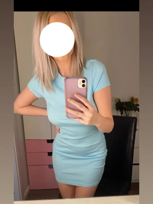 Ljusblå tight kortklänning - Säljer en ljusblå tight kortklänning med korta ärmar. Klänningen har en enkel och stilren design, perfekt för dig som gillar en clean look. Materialet känns mjukt och stretchigt, vilket gör den bekväm att bära.