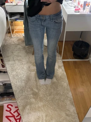Ljusblå bootcut jeans med detaljer - Säljer ett par ljusblå bootcut jeans med snygga slitningar och dekorativa detaljer på fickorna. Står ingen storlek men skulle säga att den e typ strl 32. Jag har sytt in dom lite i låren och knappen sitter lite löst(men funkar fof)💗säljer då de blivit för små för mig!