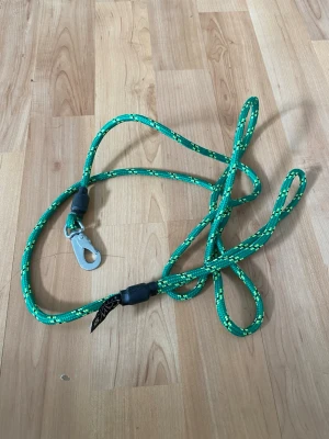 Grönt koppel från Paw of Sweden - Säljer ett grönt hundkoppel från Paw of Sweden med reflexdetaljer och metallhake. Kopplet är gjort av slitstarkt repmaterial och har svarta plastdetaljer. Perfekt för promenader med din hund.