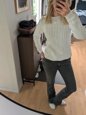Vit kabelstickad tröja - Kabelstickad tröja i vit färg med rund halsringning och ribbade muddar vid ärmslut och nederkant. Klassisk och enkel design som passar till mycket. 