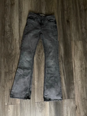 Grå bootcut jeans från Perfect Jeans - Säljer ett par gråa bootcut jeans från Perfect Jeans. Jeansen har klassisk femficksmodell, medel midja och utsvängda ben. Materialet är mjukt denim och färgen är tvättad grå som ger en cool vintagekänsla.