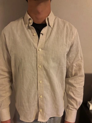 Linneskjorta Oscar Jacobsson  - Linneskjorta i färgen beige från Oscar Jacobsson. Skjortan är helt ny och tag finns kvar på skjortan. Storleken är s men är skräddad så passar även xs