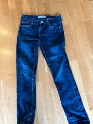 Levi's 512 Slim Taper jeans blå - Snygga blå Levi's 512 Slim Taper jeans med smal passform och avsmalnande ben. Klassisk femficksmodell med kopparfärgade nitar och kontrastsömmar. Perfekta för dig som gillar en modern och stilren look. Småslitna där nere men annars bra, strlk 158-164