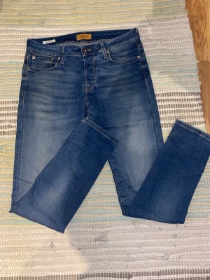 Blå slim fit jeans från Jack & Jones - Säljer ett par blå slim fit jeans från Jack & Jones, modell Glenn. Jeansen har normalhög midja och snygg tvätt. Perfekta för dig som gillar en smalare passform och stilren look. Dom är varsamt använda så inga defekter alls. Priset är inte spikat!