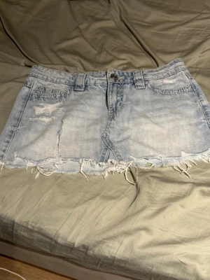 Ljusblå jeanskjol med broderade fickor - Har tyvärr gått sönder på vänster sida men annars i fint skick 