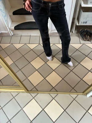 Mörkblå bootcut jeans med kontrastsömmar - Säljer ett par mörkblå bootcut jeans med vita kontrastsömmar och klassisk femficksmodell. Jeansen har låg midja och är tillverkade i ett stretchigt denimtyg som sitter snyggt på kroppen. Perfekta för dig som gillar en tidlös och avslappnad stil.