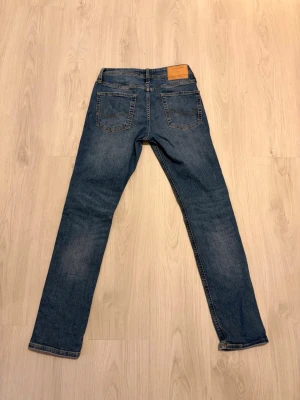 Jack & Jones Jeans - Säljer ett par blå slim jeans med slitningar på båda benen från Jack & Jones. Modellen heter slim/glenn. Jeansen har klassisk femficksdesign, normal midja och är tillverkade i denim. Perfekta för en avslappnad och trendig look. Storlek: 29/32.