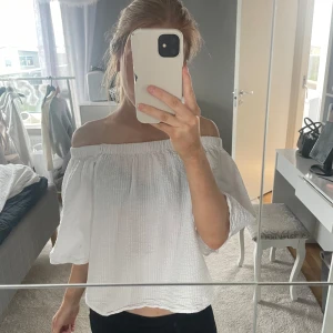 Vit offshoulder blus - Säljer en vit offshoulder blus med trekvartsärmar. Blusen har en lös passform och är tillverkad i ett lätt, strukturerat tyg. Perfekt för varmare dagar och enkel att styla med olika underdelar.