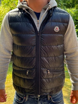 Svart dunväst från Moncler - Säljer en snygg dunväst från Moncler! Västen är i mycket bra skick och har inga defekter. Knappt använd. Om ni har några frågor så är de bara att höra av er😊
