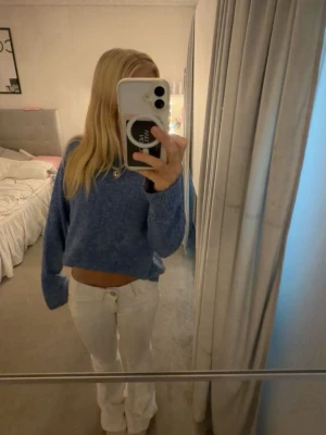 Blå stickad tröja - Mysig blå stickad tröja med avslappnad, lite croppad passform och långa ärmar. Tröjan har en enkel design utan synliga mönster och är perfekt för en snygg basic outfit