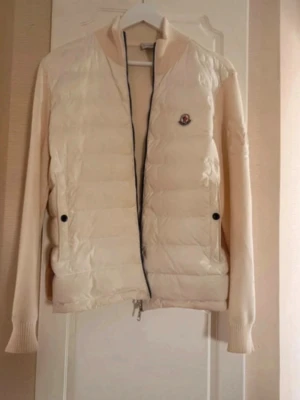 Beige dunväst med stickade ärmar - Snygg beige dunväst från Moncler med stickade ärmar och ribbade muddar. Västen har quiltad front, säljer då jag har en i svart och denna ej används🌸 skriv för prisförslag 