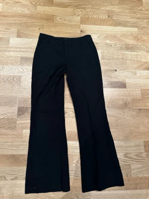 Svarta utsvängda kostymbyxor - Snygga svarta kostymbyxor med utsvängda ben . Byxorna har hällor för skärp och en stilren look som passar perfekt till en trendig outfit. Från ginatricot❣️