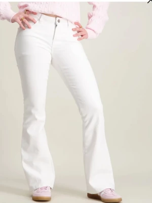 Vita bootcut jeans - Säljer ett par vita bootcut jeans med klassisk femficksdesign och normal midja. Jeansen har raka ben som går ut något nedtill och är tillverkade i ett mjukt denimtyg. Perfekta för dig som vill ha en clean och fräsch look.