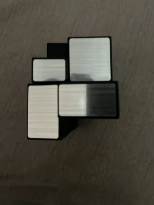 Spegelkub pussel - Unik spegelkub i svart och silver, liknande en Rubiks kub men med olika stora rektangulära bitar. Tillverkad i plast med spegelblanka ytor som reflekterar ljus. Perfekt för dig som gillar kluriga pussel och vill ha en snygg inredningsdetalj.