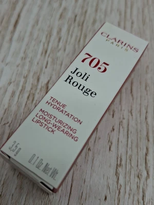 Clarins Joli Rouge 705 Soft Berry - Clarins Joli Rouge läppstift i nyansen 705 Soft Berry. Färgen är en mjuk bärton som ger återfuktning och lång hållbarhet. Förpackningen är elegant och klassisk, och innehåller 3,5 g återfuktande läppstift.
