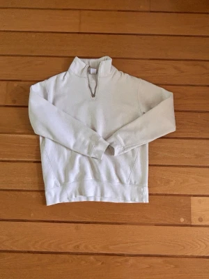 Vit halvzip tröja från Zara - Snygg vit tröja från Zara med halv dragkedja och hög krage. Tillverkad i mjukt bomullsmaterial som känns skönt mot huden. Perfekt för lager på lager och enkel att matcha med olika outfits.