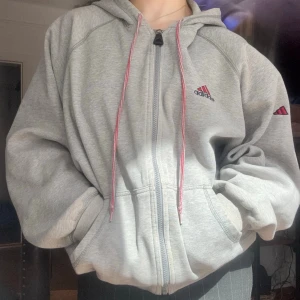 Adidas jacket  - Adidas hettejakke i grått med røde snorer.  Løs og myk, jeg er 155cm og den gir en baggy look. Kan leveres eller hentes i Frogner 