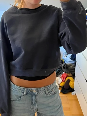Marinblå croppad sweatshirt - Säljer en marinblå croppad sweatshirt med rund hals och långa ärmar. Tröjan har en avslappnad passform och är gjord i mjukt material, perfekt för en chill och trendig look. Passar till både jeans och mjukisbyxor.