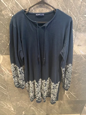 Marinblå klänning med broderi och knyt - Fin mörkblå klänning från LC Waikiki i storlek XL. Endast använd en gång och är i mycket bra skick. Snygga ljusa broderade detaljer på ärmarna och nedtill som ger klänningen ett fint och elegant utseende.  Kan självklart skicka fler bilder eller mått vid intresse! 🤍