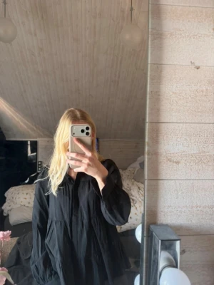 Svart vid blus med lång ärm - Säljer en svart, luftig och vid blus med långa ärmar. Blusen har en avslappnad passform och lätt rynkade detaljer som ger en trendig look. Perfekt att styla med jeans eller kjol för en cool vardagsoutfit.