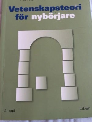 Vetenskapsteori för nybörjare - Boken 'Vetenskapsteori för nybörjare' har ett grönt omslag med vit och blå text samt en grafisk illustration av en båge i vitt. Utgiven av Liber, 2 upplagan. Perfekt som kurslitteratur för dig som vill förstå grunderna i vetenskapsteori.