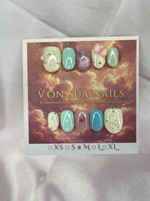 Sena (M);ExtraShortOval  - Handgjorda press-on naglar i mixade pastellfärger som mintgrön, blå, lila och cremevitt. Naglarna har detaljer som glitter, prickar, små rosetter, texten 'Hope', regnbåge och 3D-blommor. Extra korta och Ovala i formen. Perfekt för dig som vill ha en unik och lekfull look.M: 16 mm, 12 mm, 12,5 mm, 11,5 mm, 10 mm