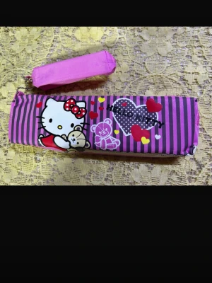 Hello Kitty rosa pennfodral - Säljer ett rosa och lila randigt pennfodral med Hello Kitty-motiv och små hjärtan. Fodralet har dragkedja och är gjort i ett glansigt tyg. Perfekt för att förvara pennor eller småprylar i väskan. Helt ny 