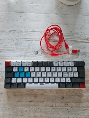 Mekaniskt tangentbord 60% layout - Säljer ett kompakt mekaniskt tangentbord med 60% layout. Tangenterna är i svart, vitt, rött och blått och har både latinska och kyrilliska tecken.