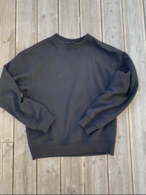 Svart H&M sweatshirt - En enkel svart sweatshirt med rund hals och ribbade muddar vid ärmar och nederkant. Tröjan är helt utan tryck eller logga och har en clean, oversized vibe. Perfekt att styla med jeans eller joggers för en chill look.