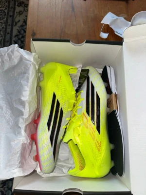 Gula Adidas fotbollsskor f50 - Säljer ett par grymma Adidas X Speedflow fotbollsskor i neon-gult och vitt med svarta detaljer. Skorna har snörning, låg profil och är designade för spel på konstgräs. Lätta material och aggressiv yttersula för maxad fart på planen.