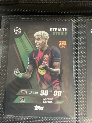 Topps fotbollskort Lamine Yamal & Salah - Två samlarkort från Topps med fotbollsspelarna Lamine Yamal (Barcelona, Stealth Strike) och Mohamed Salah (Liverpool, Black Edge Edition). Korten har färgstarka motiv och klubbarnas loggor, perfekta för dig som gillar att samla på fotbollskort.