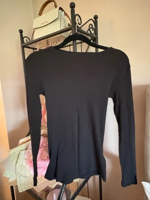 Svart ribbad långärmad topp Esmara - En svart, ribbad långärmad topp från Esmara. Toppen har en enkel och stilren design med rund halsringning och smal passform. Perfekt att styla med jeans eller kjol för en clean look.