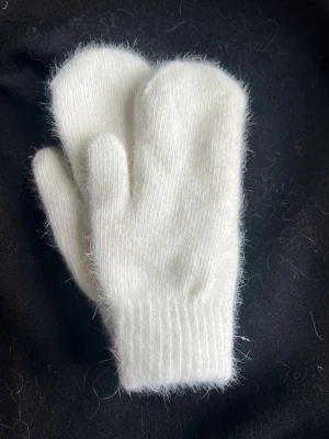 Vita stickade vantar - Mysiga vita stickade vantar med mjuk och fluffig känsla. Perfekta för kalla dagar och har en enkel, klassisk design utan mönster. Passar dig som vill ha något stilrent och varmt.
