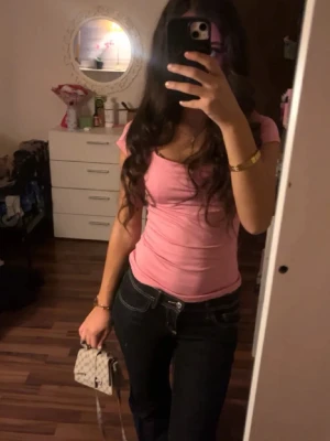 Rosa tight kortärmad topp - Säljer en söt rosa topp med tight passform och korta ärmar. Toppen har en enkel, stilren design och är gjord i ett mjukt material som sitter skönt mot kroppen. Perfekt att matcha med jeans eller kjol för en trendig look.