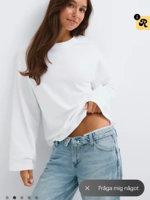 Vit långärmad topp i bomull - En basic vit långärmad topp med rund hals och avslappnad passform. Tillverkad i mjuk bomull, perfekt att styla med jeans eller kjol. Enkel och stilren design utan synliga detaljer.