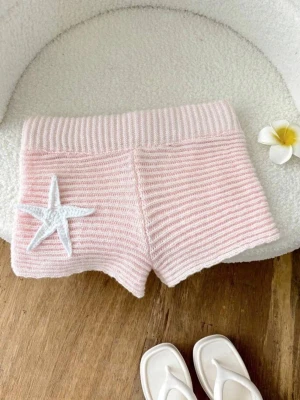 Ljusrosa stickade shorts med stjärndetalj - Säljer ett par ljusrosa stickade shorts med bred resår i midjan och en vit stjärna broderad på ena benet. Shortsen har en mjuk och bekväm känsla, perfekta för varma dagar eller mys hemma. Köpte på Plick men dom är från 