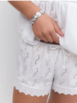 Vita broderade shorts med volangkant - Säljer ett par vita shorts i bomull med broderade detaljer och volangkant. De har elastisk midja och ett luftigt, löst passform som passar perfekt till varma dagar. Supersöta och lätta att matcha med olika toppar.