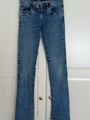 Blå bootcut jeans med fem fickor - Snygga blå bootcut jeans från LTB med klassisk femficksdesign och låg midja. Jeansen har en lätt tvättad look och raka ben som slutar i en liten utsvängning. Perfekta för en avslappnad och trendig stil. Materialet är mjukt denim i bomullsblandning. Som ni ksk ser har jeansen lite slitningar vid nedre delen så pris kan absolut diskuteras! 