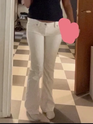 Vita bootcut jeans från Miss Me - Snygga vita bootcut jeans från Miss Me med låg midja och dekorativa sömmar. Jeansen har klassisk femficksdesign, silverfärgade knappar och är tillverkade i ett stretchigt denimtyg för en bekväm passform. vi har även sytt in dom lite i grenen så de passar ca M men inget som syns