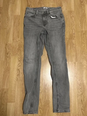 Grå jeans med smal passform - Säljer ett par grå jeans med smal passform och klassisk femficksdesign. Jeansen har dragkedjegylf och raka ben. Perfekta för dig som gillar en stilren och enkel look.
