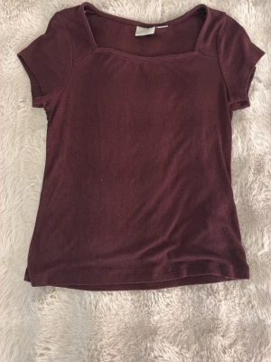 Mörkröd topp med fyrkantig ringning - En enkel och stilren mörkröd topp med korta ärmar och fyrkantig ringning. Tillverkad i mjukt bomullsmaterial som känns skönt mot huden. Perfekt att matcha med jeans eller kjol för en avslappnad look. Gina Young 158-164