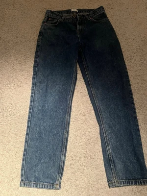 Blå jeans från grunt  - Säljer ett par klassiska blå jeans från grunt med rak passform och hög midja. Jeansen har fem fickor, bälteshällor och stängs med knapp och dragkedja. Perfekta till vardags och enkla att styla med olika toppar. Inte så mycket använda och i ett väldigt bra skick! Säljer för 300 kr kan gå med på priser ner till 200 kr!