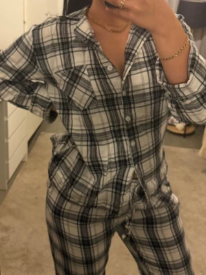 Rutig pyjamas i svartvitt - Mysig pyjamas med svartvitt rutmönster. Skjortan har knappar framtill, krage och två bröstfickor. Byxorna har resår i midjan och snörning för extra komfort. Perfekt för slappa dagar hemma eller en skön natts sömn. Bara testat utan prislapp 🌸