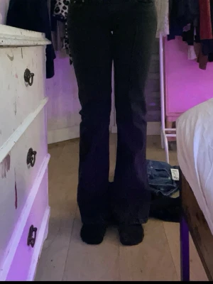 Svarta bootcut jeans - Säljer ett par svarta bootcut jeans med klassisk femficksmodell och låg midja. Jeansen har utsvängda ben och är perfekta för dig som gillar en retrostil. Materialet är denim med lite stretch för extra komfort.