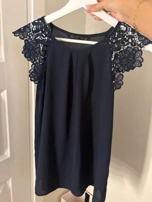 Mörkblå blus med spetsärmar - Säljer en mörkblå blus från Zara med vackra spetsdetaljer på axlarna. 