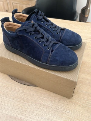 Mörkblå mockasneakers Christian Louboutin - Snygga mörkblå sneakers i mocka från Christian Louboutin med svarta snören och svart sula. Klassisk låg modell med diskreta sömmar och lyxig känsla. Perfekta för dig som vill ha stilrena och exklusiva sneakers i garderoben. Storlek 44-45 lägg ett bud 