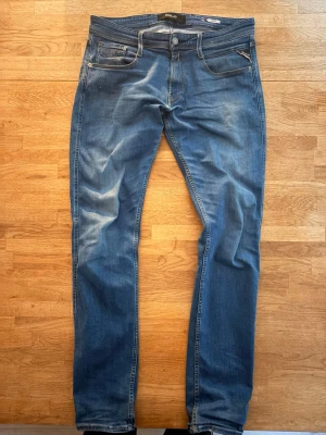 Replay Jeans  - Snygga blå slim fit jeans med klassisk femficksdesign och dragkedjedetalj på ena fickan. Dem är i storlek 32 34. Jeansen har en lätt tvättad look och smal passform som sitter tajt längs benen. Perfekta för en trendig och avslappnad stil. På fjärde bilden ser man en liten defekt annars inga fler. Skriv vid minsta fundering 👍👍