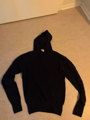 Mörkblå Kashmir hoodie med huva - En stilren mörkblå hoodie med huva och långa ärmar. Tröjan har en klassisk passform och är tillverkad i materialet Kashmir som passar perfekt till en avslappnad look. Inga synliga loggor eller tryck, enkel och clean design.