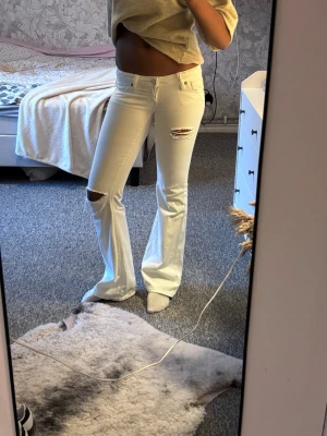 Vita booycut jeans med slitningar - Säljer ett par vita jeans och slitningar vid knäna. Jag är 1,77m lång